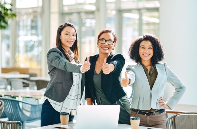 Cropped shot of young businesswomen showing thumbs up while having a meeting in the convention centre